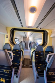 Modern train interior with yellow-blue seats and bright lighting, test run on the new Hermann-Hesse
