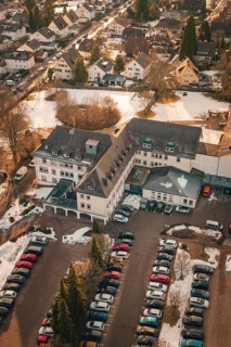 A large building with an adjacent parking lot and a few snow-covered cars, district office,