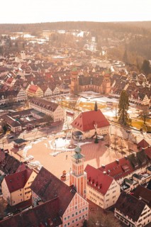 City view with church tower and historic buildings covered by light snow at sunset, Freudenstadt,