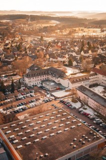Aerial view of a city with many buildings, warm sunlight, parked cars and winter landscape,