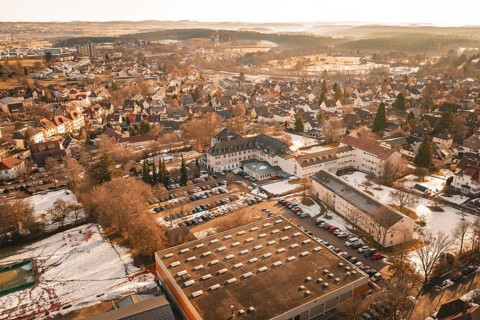 Panoramic view of a snowy city with buildings and trees from a bird's eye view in warm light,