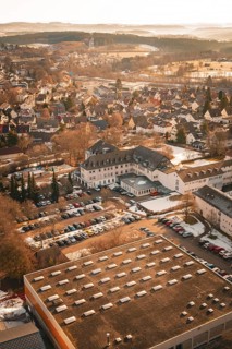 Urban area in winter with snow-covered houses and roads in warm sunlight from a bird's eye view,