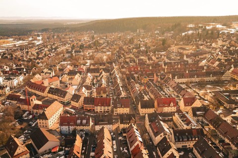 Aerial view of a winter town with rustic houses and snow-covered streets in warm lighting,