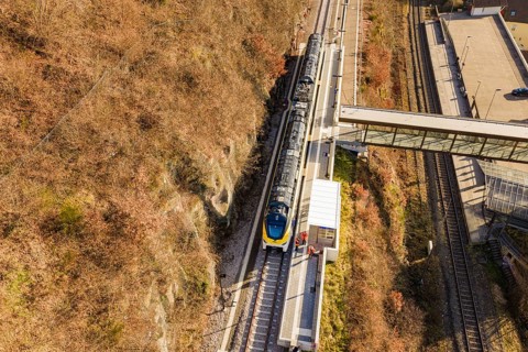 Bird's-eye view of a train station with bridge and autumnal tracks, test run on the new
