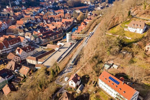 Urban landscape with railway line and river, surrounded by houses from aerial view, test run on the