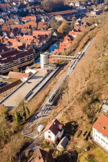 Aerial view of a city with railroad tracks and river surrounded by houses, test run on the new