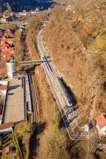 Aerial view of a railway line along a wooded slope with urban surroundings, test run on the new