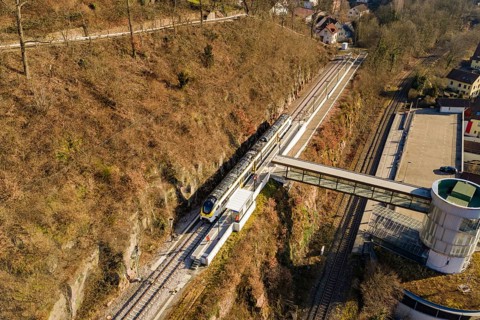 Overview of train journey through hilly vegetation and bridge in urban surroundings, test run on