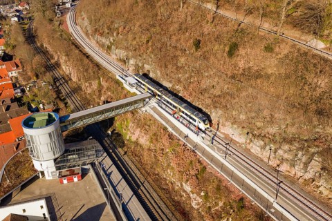 Train ride across bridge in hilly landscape surrounded by vegetation and town houses, test trip on