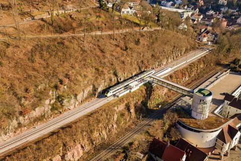 Aerial view of a railway station in an urban area, surrounded by nature and architecture, test run