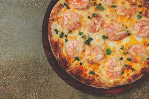 Four cheese pizza with shrimp and fresh microgreens, served on a wooden board, homemade, no people