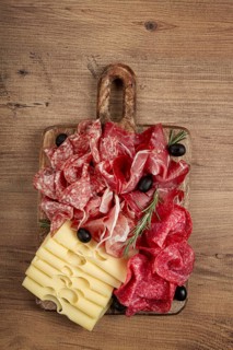 Assorted meat, appetizer, prosciutto, salami and ham, with maasdam cheese and olives, on a wooden