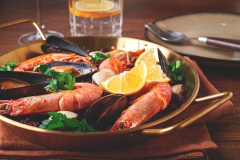 Seafood and black rice paella, in a frying pan, homemade, on a wooden table, no people