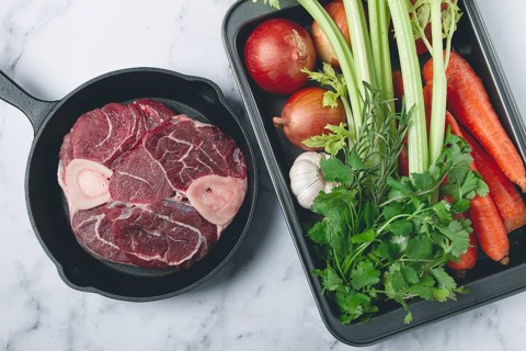 Sknuckle on the bone, raw meat for ossobuco, in a cast-iron pan, baking sheet with vegetables, top