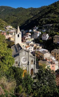 View of picturesque village of Riomaggiore with church and colorful houses in a green, hilly