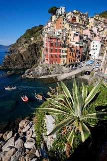 Colourful houses under blue sky, view of the fishing village of Riomaggiore, boats in the harbour,