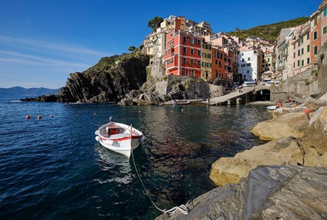White boat, colorful houses under blue sky, view of the fishing village of Riomaggiore, port,