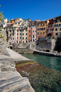 Colourful houses along a rocky coast with clear sea water under blue sky, fishing village of