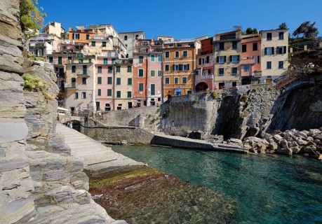 Colourful houses along a rocky coast with clear sea water under blue sky, fishing village of