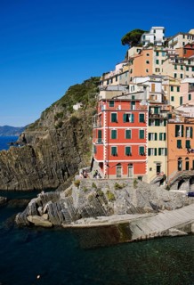 Colourful houses on rocky coast under blue sky, fishing village of Riomaggiore, Cinque Terre, La