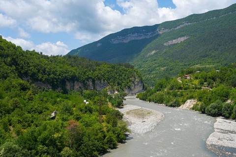 River flows through a wooded valley in the mountains under a cloudy sky, Rioni river near Alpana,