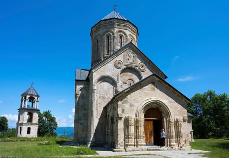 Romanesque church with bell tower in rural area under clear blue sky, Nikorzminda Cathedral,