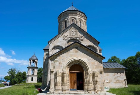 Stone church with detailed façade under clear blue sky, Nikorzminda Cathedral, Nikorzminda