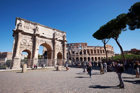 Arch of Constantine and Colosseum surrounded by tourists under blue sky, Rome, Lazio, Italy