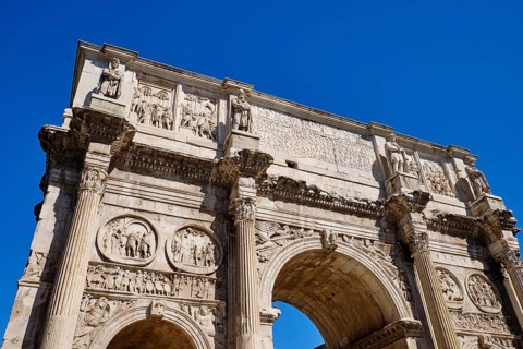 Arch of Constantine with ornate reliefs under blue sky, Rome, Lazio, Italy
