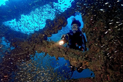 Underwater photo diver dives through parts of former sunken tin excavator Boonsung wreck off the