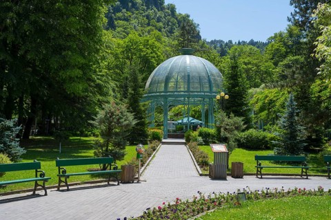 A path through a green park leads to a pavilion surrounded by flowers and trees, pavilion with