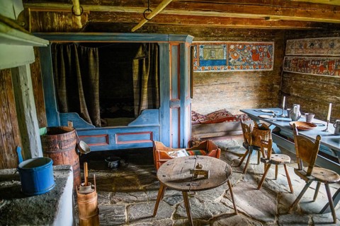 Rustic dining room with wooden table and chairs, wall paintings and antique charm in the birthplace