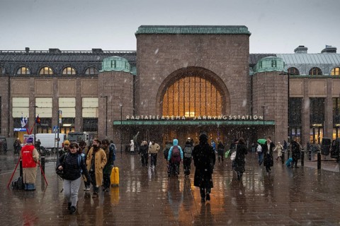 Busy side entrance to Central Station with Christmas decoration during snowfall, Helsinki, Finland