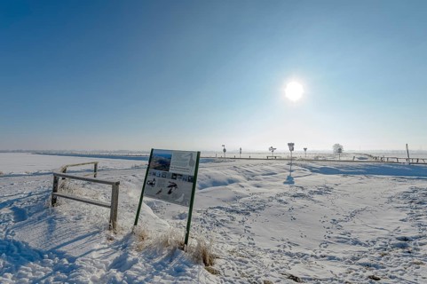 Snowy landscape with information board under bright blue sky in the Ochsenmoor nature reserve area,