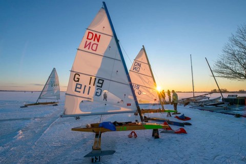 Ice sailboats in evening light and bright sun on the shore of a frozen lake Dümmer, Dümmer See,