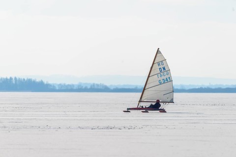Ice sailor glides over icy surface under clear sky in wintry landscape, Lembruch, Diepholz