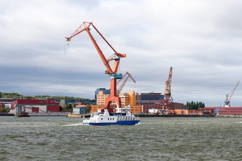Large industrial port crane and ship on water under cloudy sky in Gothenburg harbour, Gothenburg,