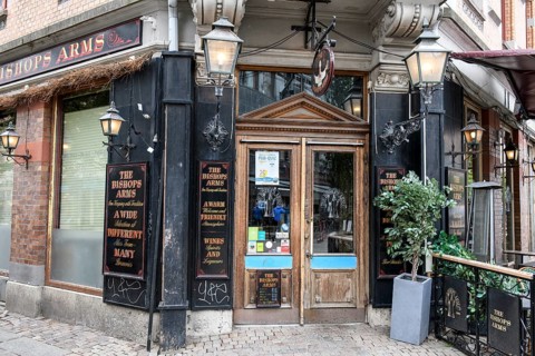 Historic pub entrance with decorative lanterns and signs, looks inviting and traditional,