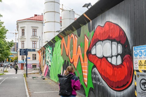 Colourful graffiti on an urban street scene with eye-catching lip motifs is viewed by a young