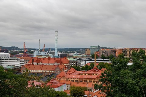 View of an urban landscape from Skansen with industrial elements and red roofs under a cloudy sky,
