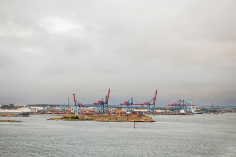 View of container bridges in Gothenburg harbour with cranes and water in the foreground under grey
