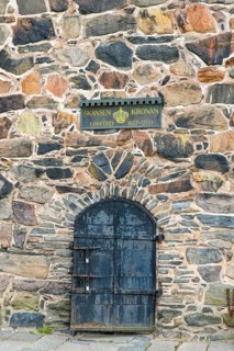Historic stone wall with a metal door and a sign about Skansen Kronan, detail of an old stone wall