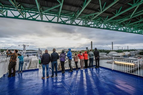 Group of people on a ship deck looking at the harbor crossing under the Älvsborgsbron suspension