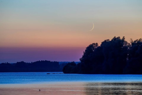 Delicate crescent moon over quiet Dümmer Lake late in the evening at sunset, Lembruch, Dümmer See,