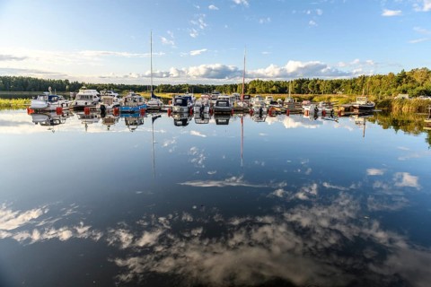 Several boats are moored in the quiet pleasure boat harbor of Ekenäs, water reflects the sky,