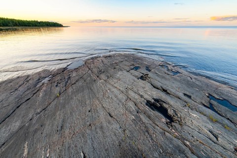 Far-reaching view of the quiet lake Vänern with gently sloping granite rocks archipelago under calm