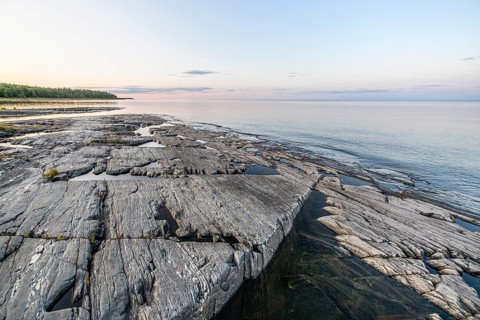 Far-reaching view of the quiet lake Vänern with gently sloping granite rocks archipelago under calm