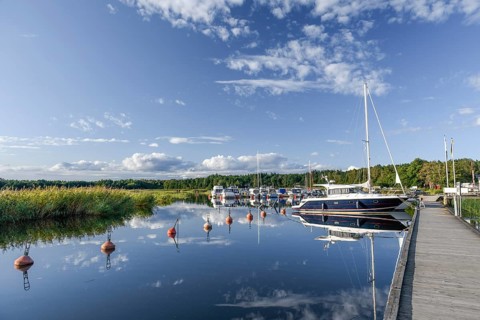 Several boats and a larger sailing yacht are moored in the quiet sports boat harbour of Ekenäs,