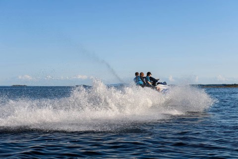 People ride fast across Lake Vänern on a jet ski and generate waves, Värmlandsnäs peninsula,