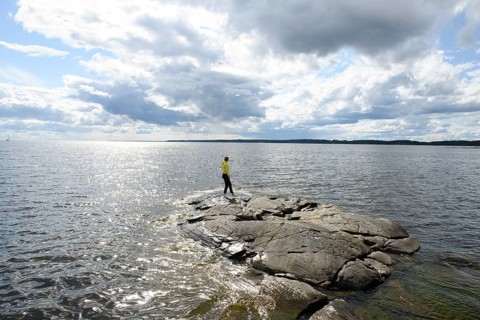 Young woman girl standing on archipelago on rocks at Lake Vänern under cloudy sky, Värmlands län,